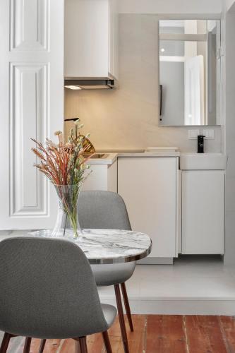 a table with two chairs and a vase of flowers at Small Design Studio - Rosa, Bairro Alto in Lisbon