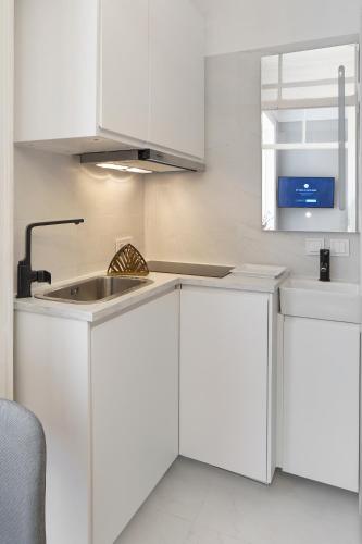 a kitchen with white cabinets and a sink at Small Design Studio - Rosa, Bairro Alto in Lisbon