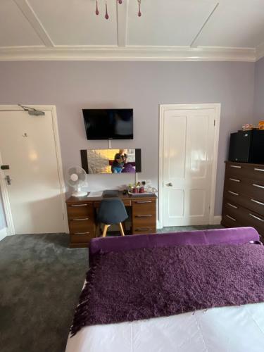 a bedroom with a purple bed and a desk at Ashmira Guest House in Weymouth