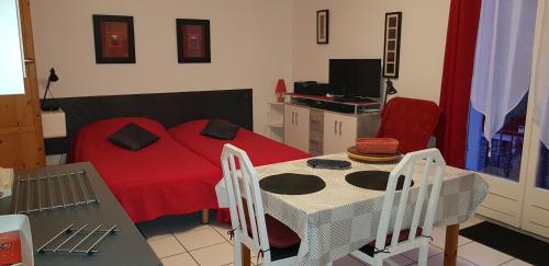- une chambre avec un lit rouge, une table et des chaises dans l'établissement Joli Studio centre ville Digne les Bains Galion 80, à Digne-Les-Bains