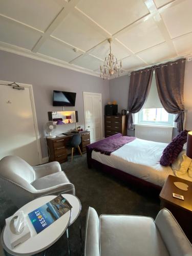 a bedroom with a bed and a chair and a desk at Ashmira Guest House in Weymouth