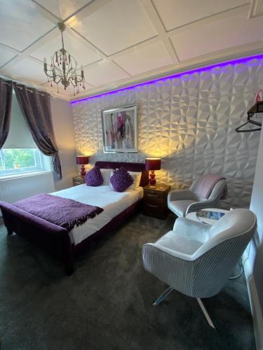 a bedroom with a bed and a chair and purple lighting at Ashmira Guest House in Weymouth
