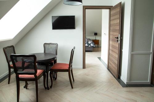 ein Esszimmer mit Tisch und Stühlen und einem Fernseher in der Unterkunft Czarna Dama Apartamenty in Janowiec