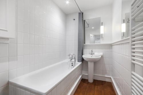 un bagno bianco con vasca e lavandino di The Upper House - Fitzrovia - by Frankie Says a Londra