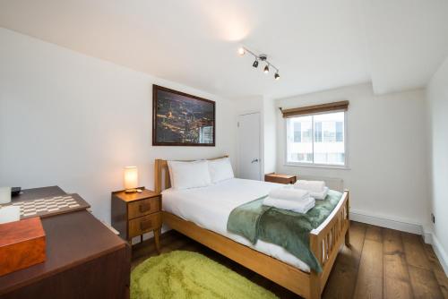 um quarto com uma cama, uma secretária e uma janela em Views For Days - Fitzrovia - by Frankie Says em Londres