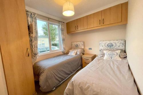 2 camas en una habitación pequeña con ventana en Relaxing Family Caravan stay in the lakes, en High Hesket