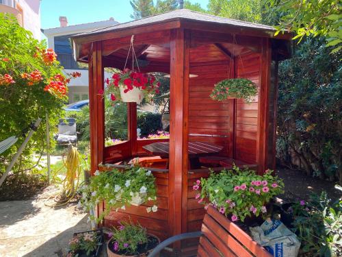 a wooden gazebo with flowers in a garden at Apartments and bungalows vila Dalibor in Nin