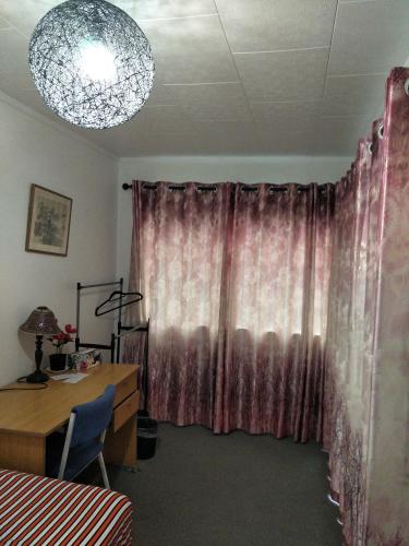 a room with a desk and a pink curtain at Wendy's Holiday Home in Auckland