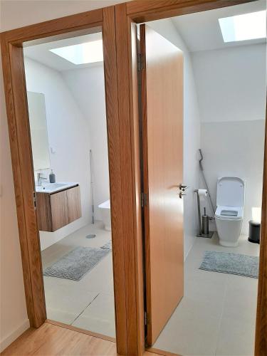 a bathroom with a toilet and a sliding glass door at Casa das Camélias Garden Guesthouse in Aveiro