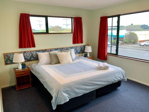 a bedroom with a large bed with red curtains at 3 Bedroom Apartment, Kaikoura in Kaikoura