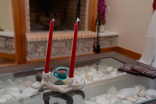 three red candles sitting in a tray of rocks at Dio Guesthouses in Leonidion