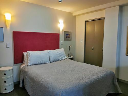 a bedroom with a large bed with a red headboard at The Anchorage Apartments in Mount Maunganui