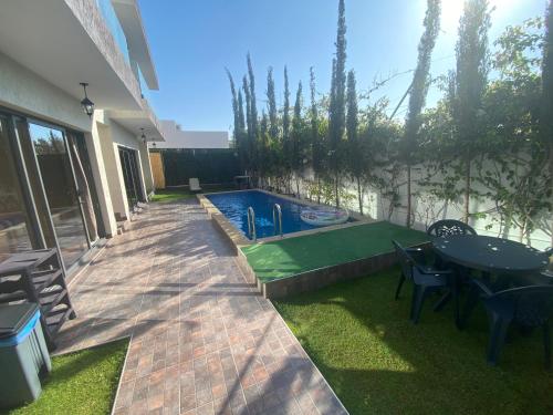 um quintal com uma piscina, uma mesa e cadeiras em VILLA AMALOU AVEC PISCINE FAMILLE UNIQUEMENt em Agadir