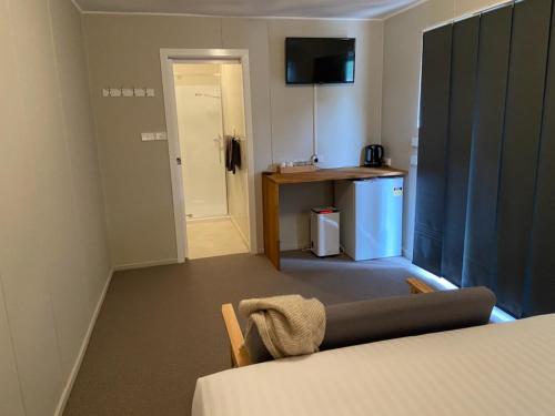 um quarto com uma cama, uma mesa e uma secretária em The Railway Hotel em Queenstown