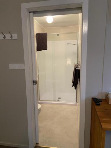 um chuveiro com uma porta de vidro na casa de banho em The Railway Hotel em Queenstown