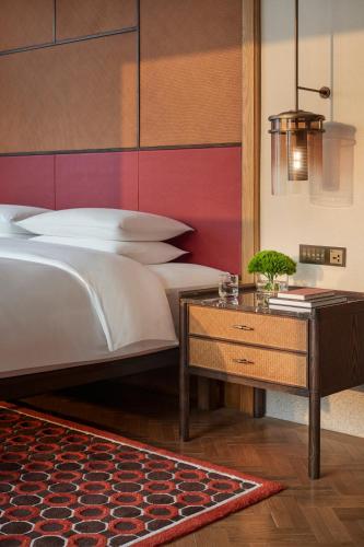 a bedroom with a bed and a nightstand with a table at Andaz Xiamen, By Hyatt in Xiamen