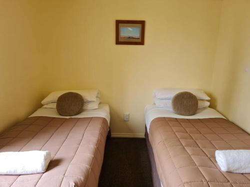 two beds in a hotel room with towels on them at The Cabin, Omahau Downs in Twizel