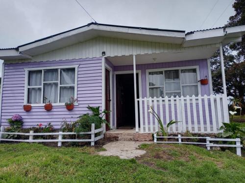 ein lila Haus mit einem weißen Zaun davor in der Unterkunft Casa Chicua in Sabanilla