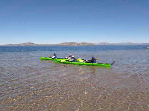 a group of people in a green canoe on the water at "Casa de Valentin" in Llachon