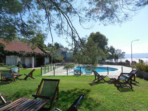 a group of chairs sitting in the grass near a swimming pool at Aguada Chica Bungalows in Villa Carlos Paz
