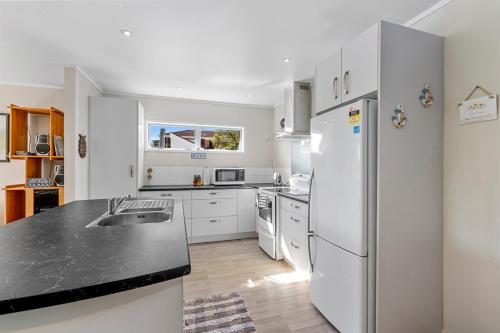 a kitchen with white appliances and a black counter top at Ota Point Paradise - Whangaroa Holiday Home in Whangaroa