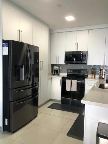 a kitchen with black appliances and white cabinets at JF Three Bedroom Apartment in Tegucigalpa