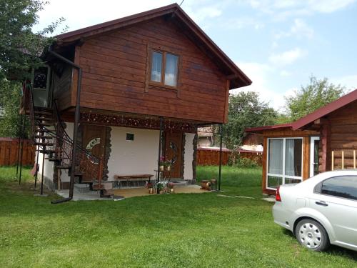a house with a porch and a car parked in the yard at Pidkova in Verkhovyna