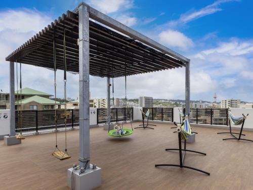 a rooftop deck with swings and chairs on a roof at エンズ　マリーナ　イン　マシキ　コンド・ホテルズ in Ginowan