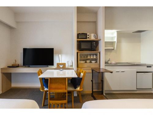 a kitchen and a dining room with a table and a television at エンズ　マリーナ　イン　マシキ　コンド・ホテルズ in Ginowan