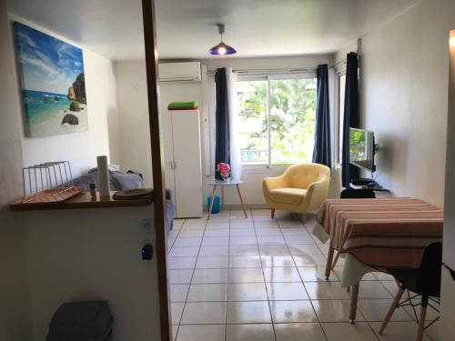 ein Wohnzimmer mit einem Bett, einem Tisch und einem Fenster in der Unterkunft La Plage Dorée in Saint-Pierre