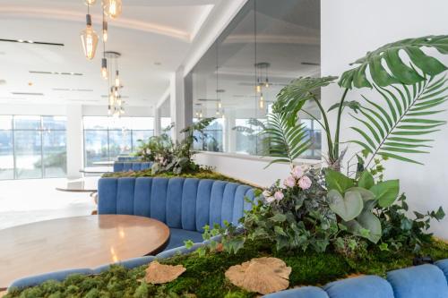 a lobby with blue couches with plants and a table at Mirage Beach Spa Hotel in Eforie Nord
