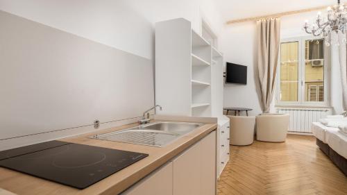 een keuken met een wastafel en een woonkamer bij Apartments ART TEATRO in Rijeka