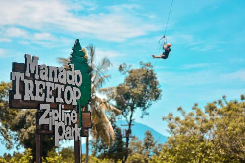 a man hanging from a zip line over a sign at Grand Luley Manado in Manado