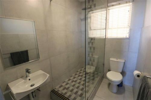 a bathroom with a shower and a toilet and a sink at Camarque 28 in Umdloti
