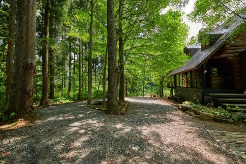 a dirt road next to a cabin in the woods at SUNNSNOW Loghouse in Otari