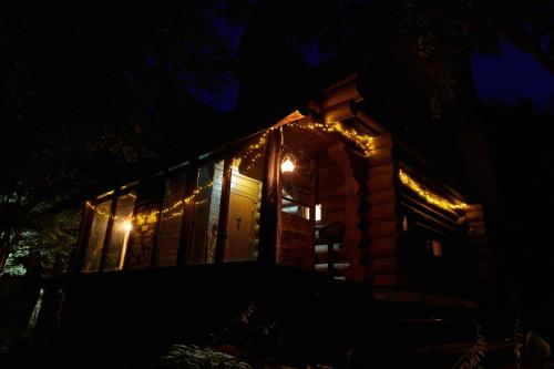 a cabin lit up at night with lights at SUNNSNOW Loghouse in Otari
