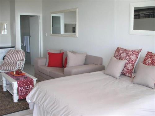 a bedroom with a white bed and a couch at Camarque 28 in Umdloti