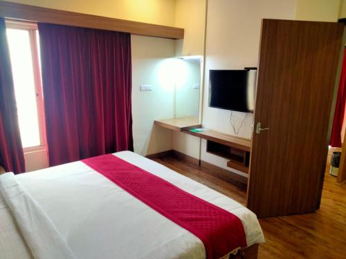 a hotel room with a bed and a flat screen tv at Hotel Parsons Court in Dindigul