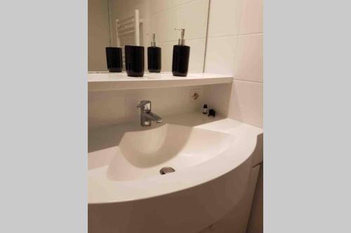 ein Badezimmer mit einem weißen Waschbecken und einem Spiegel in der Unterkunft L'Appart de La Baule, piscines , proche mer. in La Baule