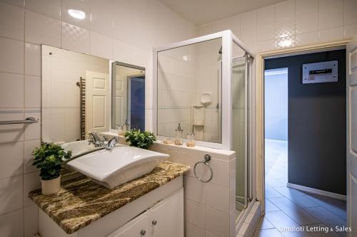 a white bathroom with a sink and a shower at 8 Waterfront in Umdloti