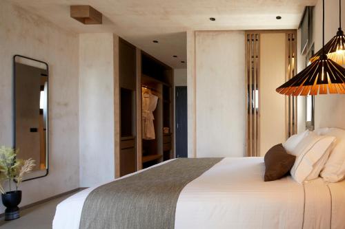 a bedroom with a large white bed and a mirror at North Santorini - A Luxury Spa Hotel in Pirgos