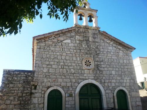 a church with a steeple and a clock on it at Apartments Valentina Tisno in Tisno