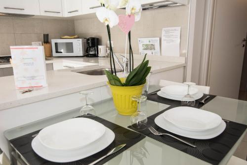 a kitchen with two white plates and a yellow vase at Geranio-Buganville-Viola in Arco