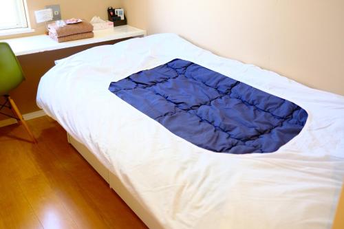 a bed with a blue blanket on top of it at コージーイン 東京桜新町 in Tokyo