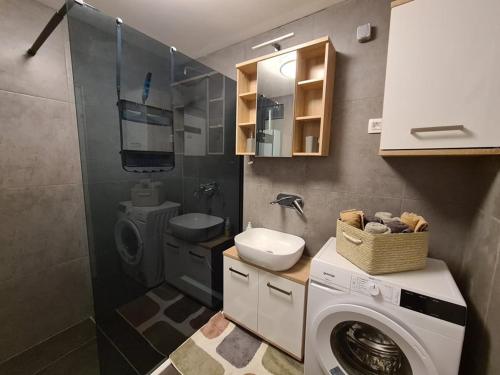 uma casa de banho com uma máquina de lavar roupa e um lavatório em Valkane beach studio apartment em Pula