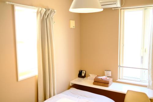 a bedroom with a bed and two windows at コージーイン 東京桜新町 in Tokyo
