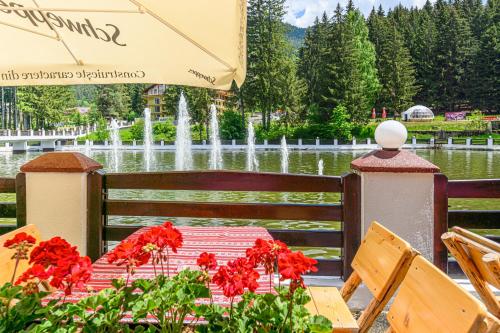 a table with red flowers in front of a fountain at Aurelius Imparatul Romanilor Hotel & SPA in Poiana Brasov