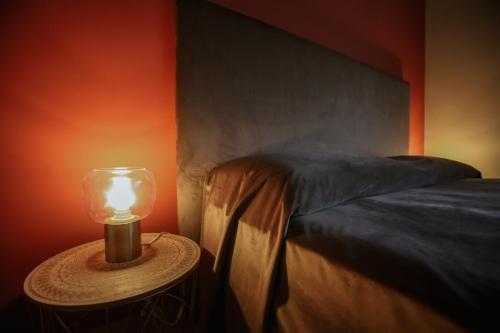 a lamp on a table next to a bed at CA'du LIN - Jacuzzi e Piscina in Cisterna dʼAsti