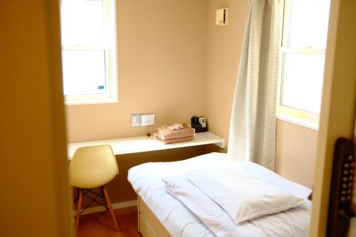 a small room with a bed and two windows at コージーイン 東京桜新町 in Tokyo