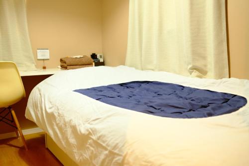 a white bed with a blue blanket on it at コージーイン 東京桜新町 in Tokyo